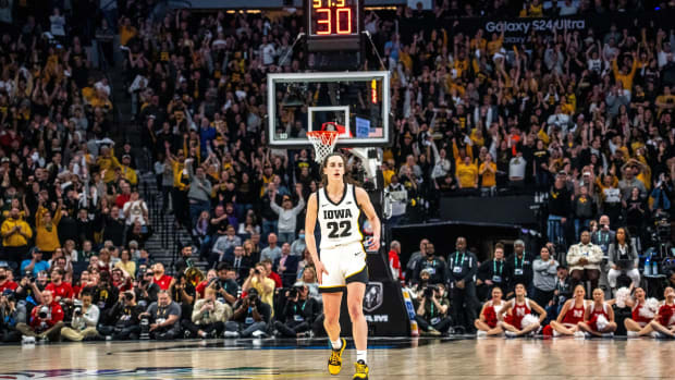 Caitlin Clark looks on from midcourt in front of a crowd during a game.